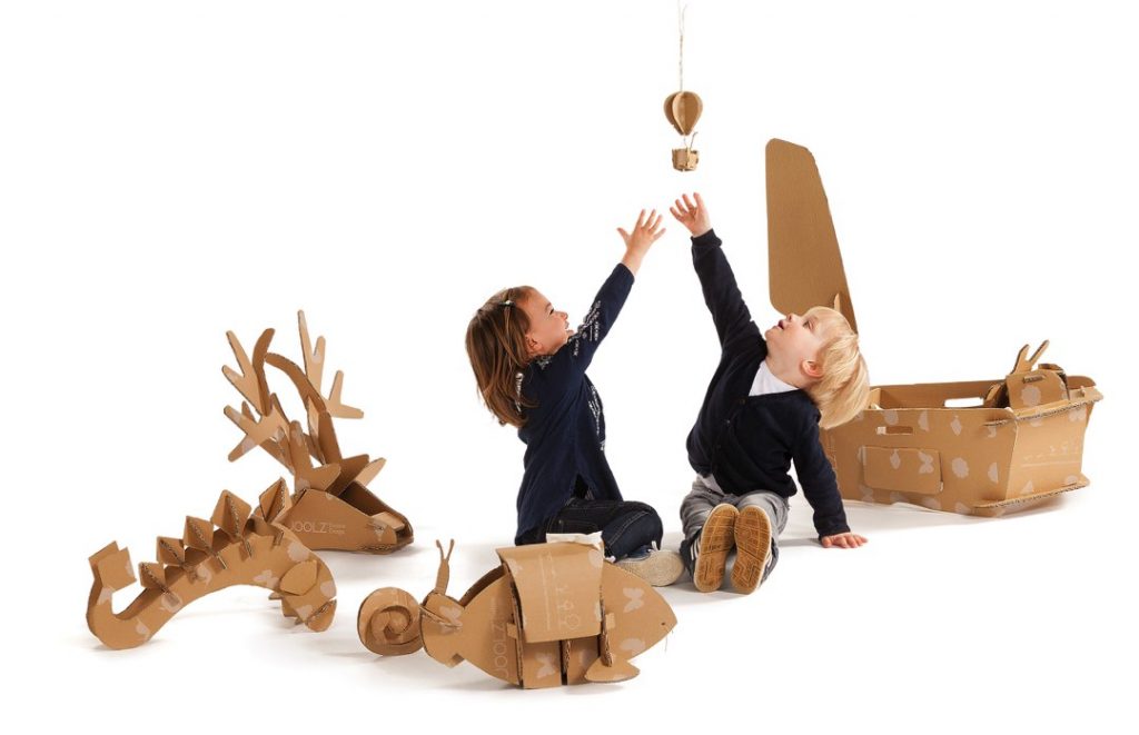Happy children playing with transformable cardboard packaging.