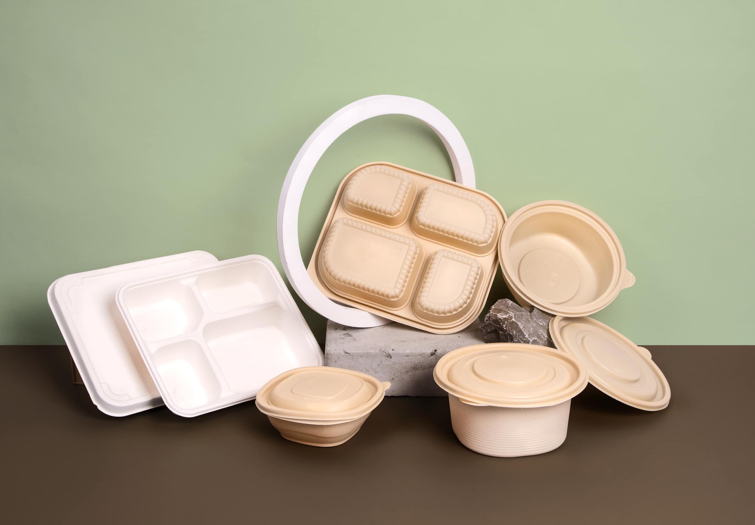 White and brown bioplastic cornstarch packaging container on a green and brown background.