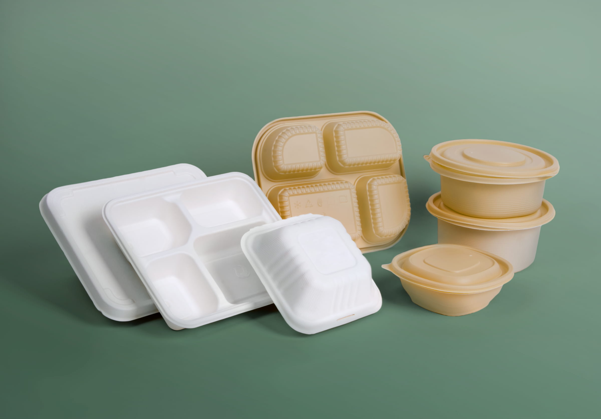 White and brown bioplastic cornstarch packaging container on a green background.